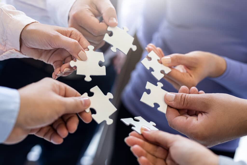 a group of business people assembling jigsaw puzzle.